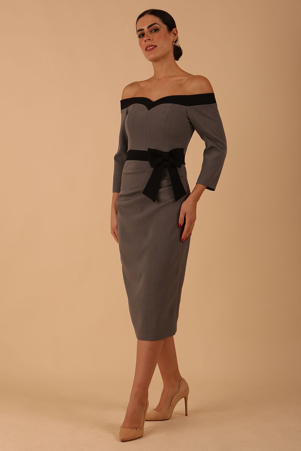 Model wearing a diva catwalk Brittany Off Shoulder Bow detail Pencil Dress with 3/4 sleeves and knee length in Sandshell Beige and Black colour 
