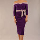 Model wearing a diva catwalk Brittany Off Shoulder Bow detail Pencil Dress with 3/4 sleeves and knee length in Deep Purple and Thunder Bird colour