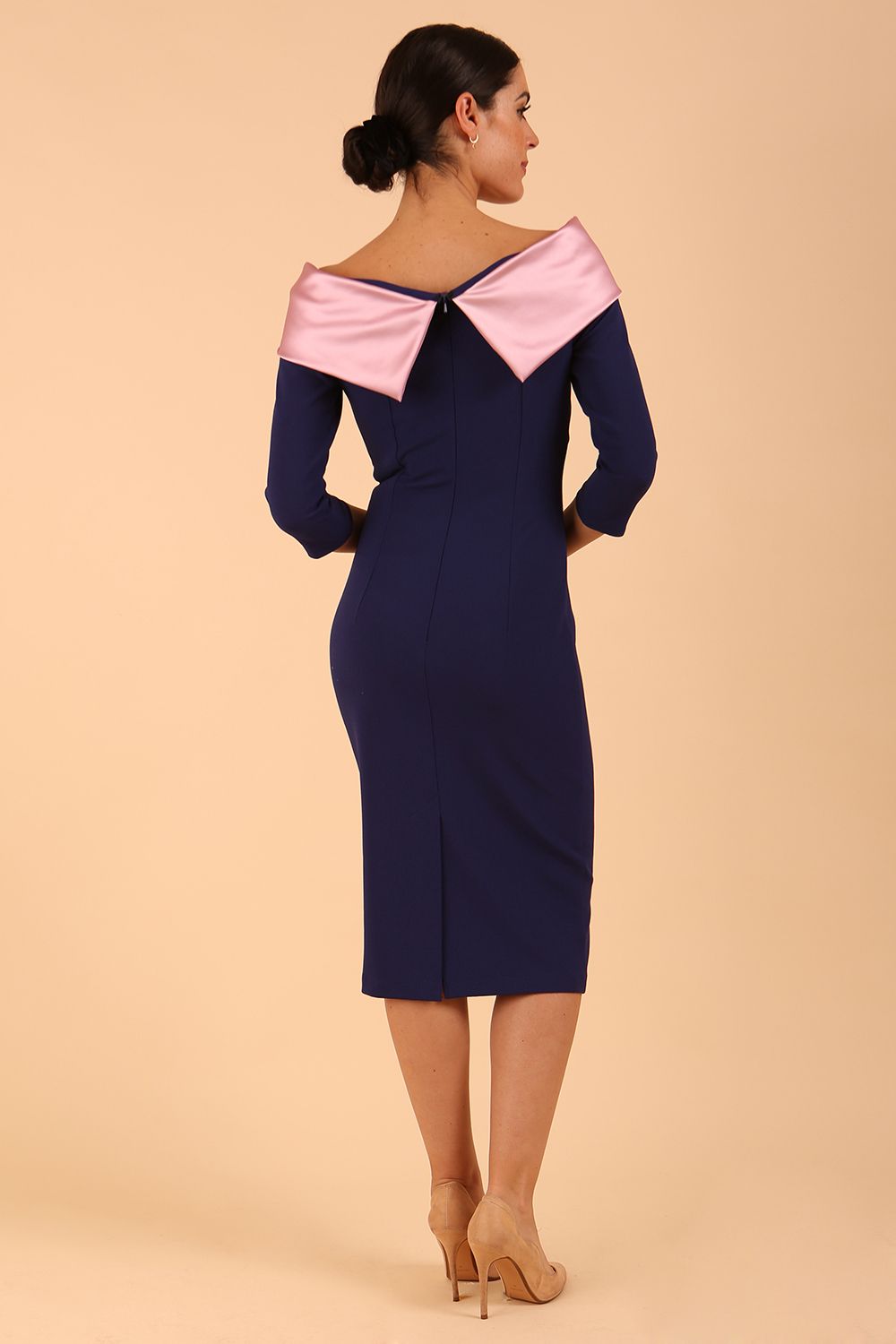 Model wearing a Rosalind Off Shoulder Bow Detail Pencil Dress 3/4 sleeve in Navy Blue/ Pink contrast