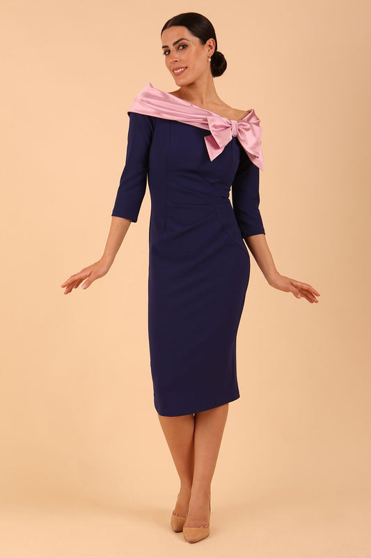 Model wearing a Rosalind Off Shoulder Bow Detail Pencil Dress 3/4 sleeve in Navy Blue/ Pink contrast