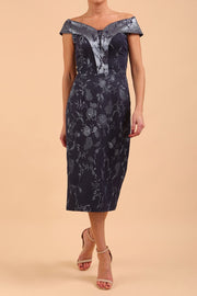 A model wearing a off shoulder pencil dress in Metallic Floral Jacquard and Mirage fabric in navy blue colour front 