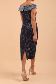 A model wearing a off shoulder pencil dress in Metallic Floral Jacquard and Mirage fabric in navy blue colour back