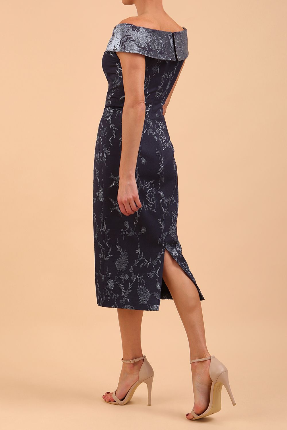 A model wearing a off shoulder pencil dress in Metallic Floral Jacquard and Mirage fabric in navy blue colour back