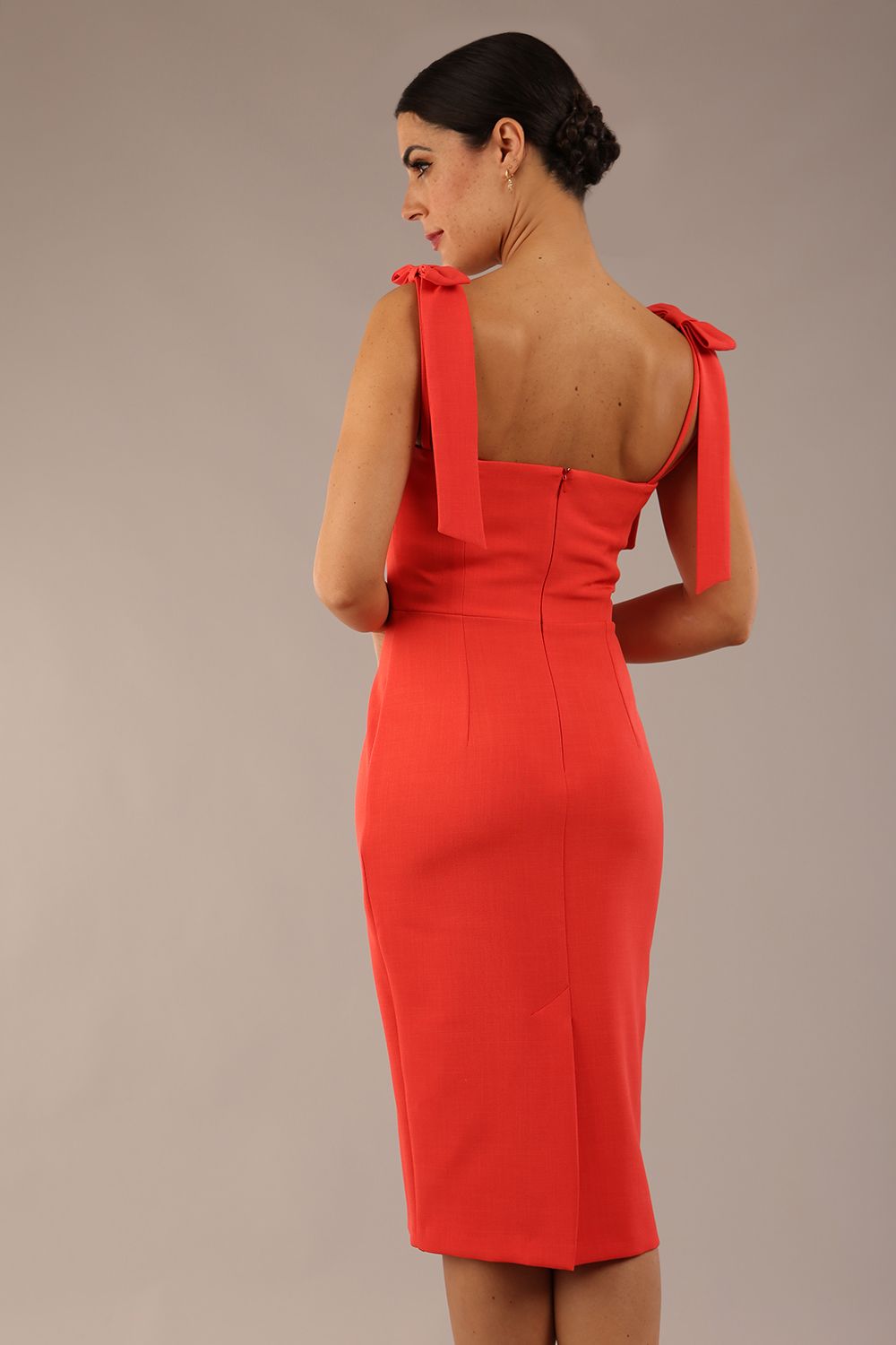 brunette model wearing a diva catwalk Philippa Pencil Wiggle Dress sleeveless style, tie detail on the shoulders knee length and sweetheart neckline in grenadine orange colour back