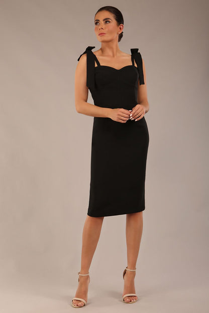 brunette model wearing a diva catwalk Philippa Pencil Wiggle Dress sleeveless style, tie detail on the shoulders knee length and sweetheart neckline in black colour front 