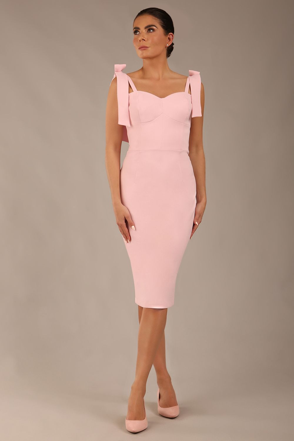 brunette model wearing a diva catwalk Philippa Pencil Wiggle Dress sleeveless style, tie detail on the shoulders knee length and sweetheart neckline in crystal pink colour front 