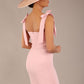brunette model wearing a diva catwalk Philippa Pencil Wiggle Dress sleeveless style, tie detail on the shoulders knee length and sweetheart neckline in crystal pink colour back with hat