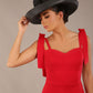brunette model wearing a diva catwalk Philippa Pencil Wiggle Dress sleeveless style, tie detail on the shoulders knee length and sweetheart neckline in scarlet red colour front with hat