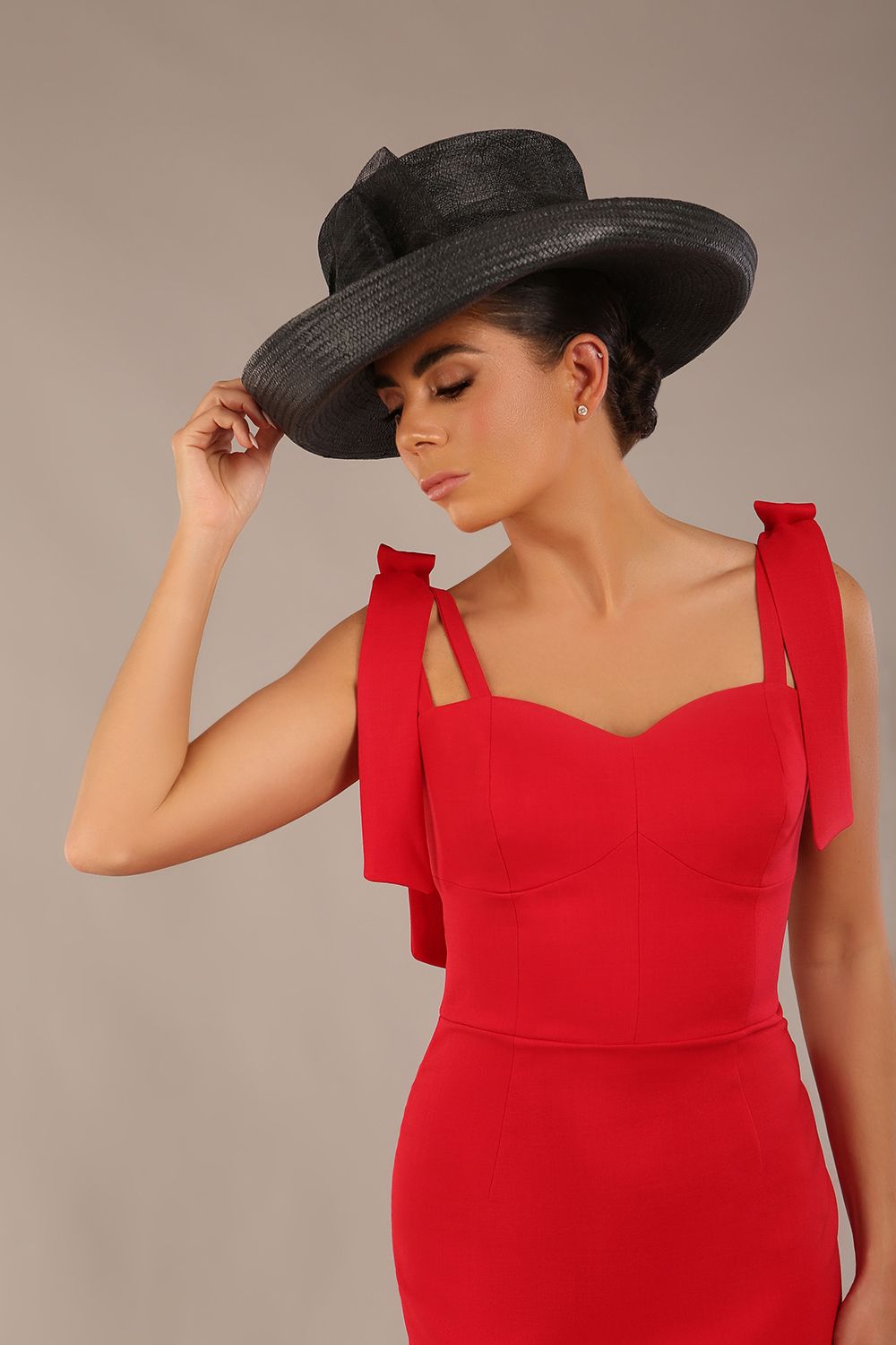 brunette model wearing a diva catwalk Philippa Pencil Wiggle Dress sleeveless style, tie detail on the shoulders knee length and sweetheart neckline in scarlet red colour front with hat