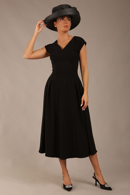 brunette model is wearing a diva catwalk Audrey a-line Dress sweetheart neckline and With Pockets and sleeveless with ankle length black colour front with a hat