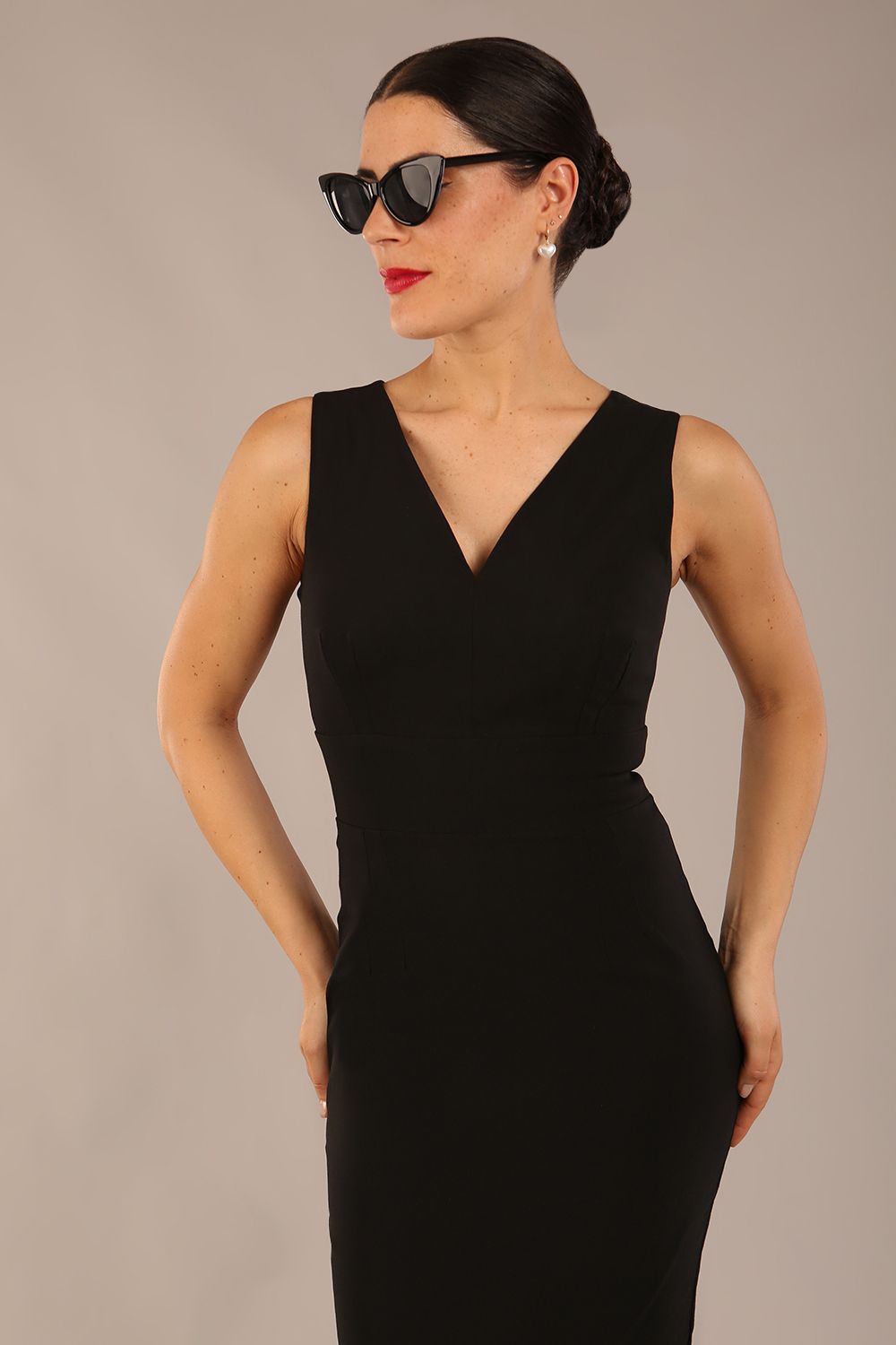 brunette model is wearing a diva catwalk Carrie Pencil Wiggle Dress sleeveless v neck front and back knee length in black colour front image with sunglasses