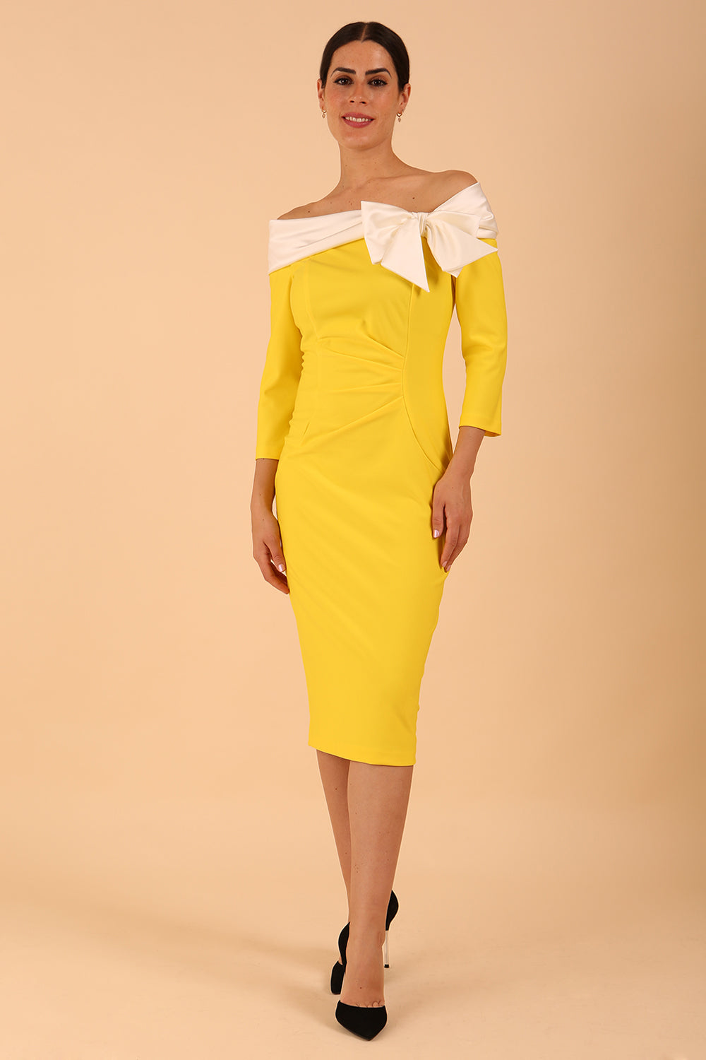 Model wearing a Rosalind Off Shoulder Bow Detail Pencil Dress 3/4 sleeve in Blazing Yellow / Ivory cream contrast