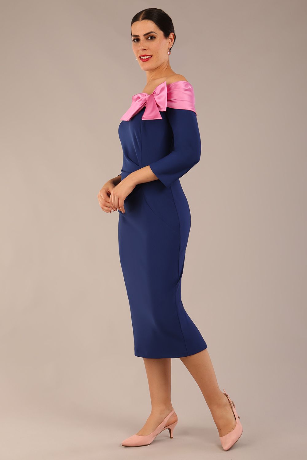 Brunette Model is wearing a Rosalind Off Shoulder Bow Detail Pencil Dress 3/4 sleeve in Navy Blue/ Pink contrast front image