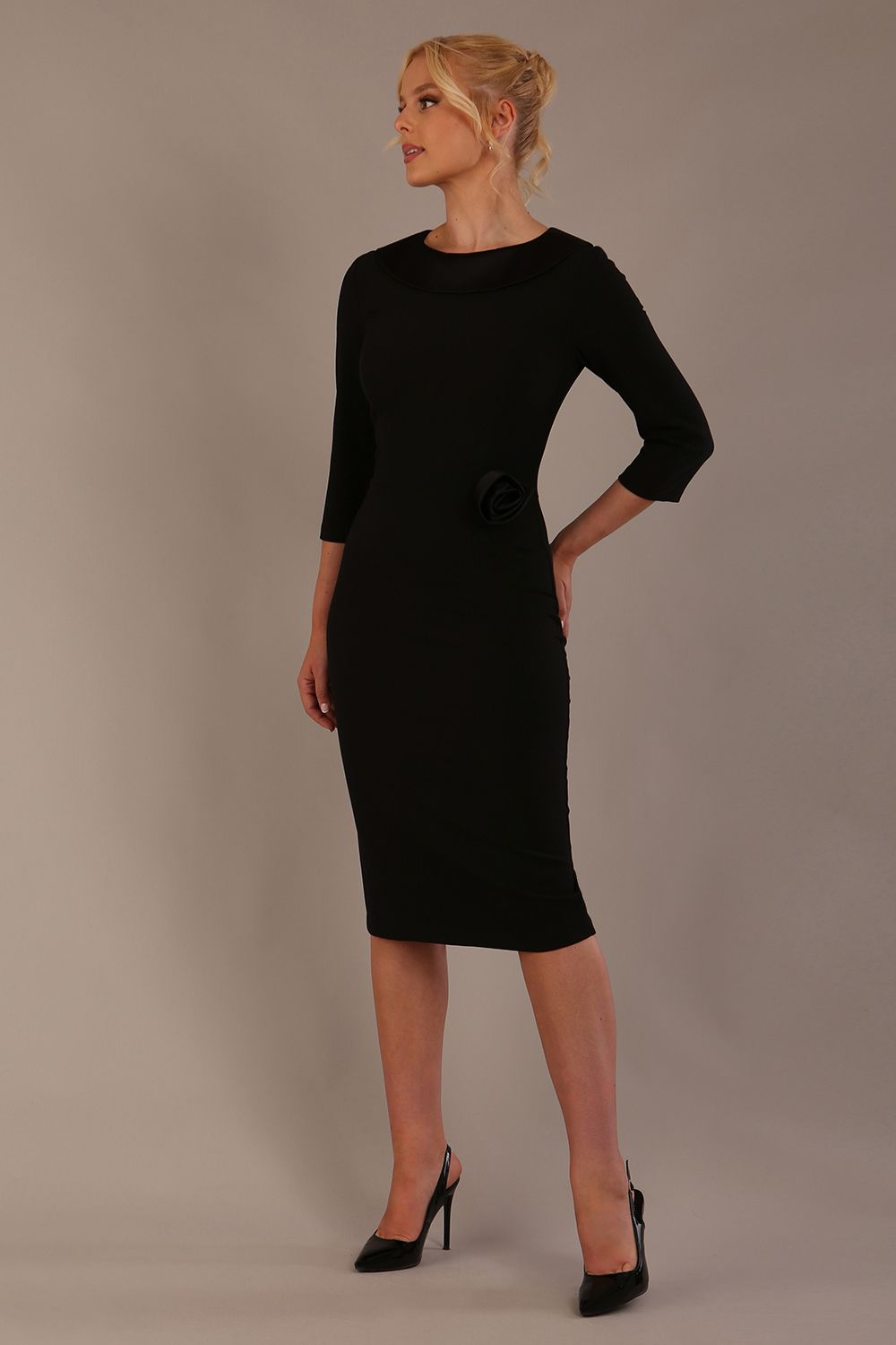 Woman wearing a Heathcote Floral Detail Pencil Dress with a plain background in black front view