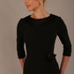 Woman wearing a Heathcote Floral Detail Pencil Dress with a plain background in black close up