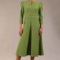 A model wearing a red, 3/4 sleeve A-line dress with pockets, featuring a boat neckline and vent at the centre back (Citrus Green)
