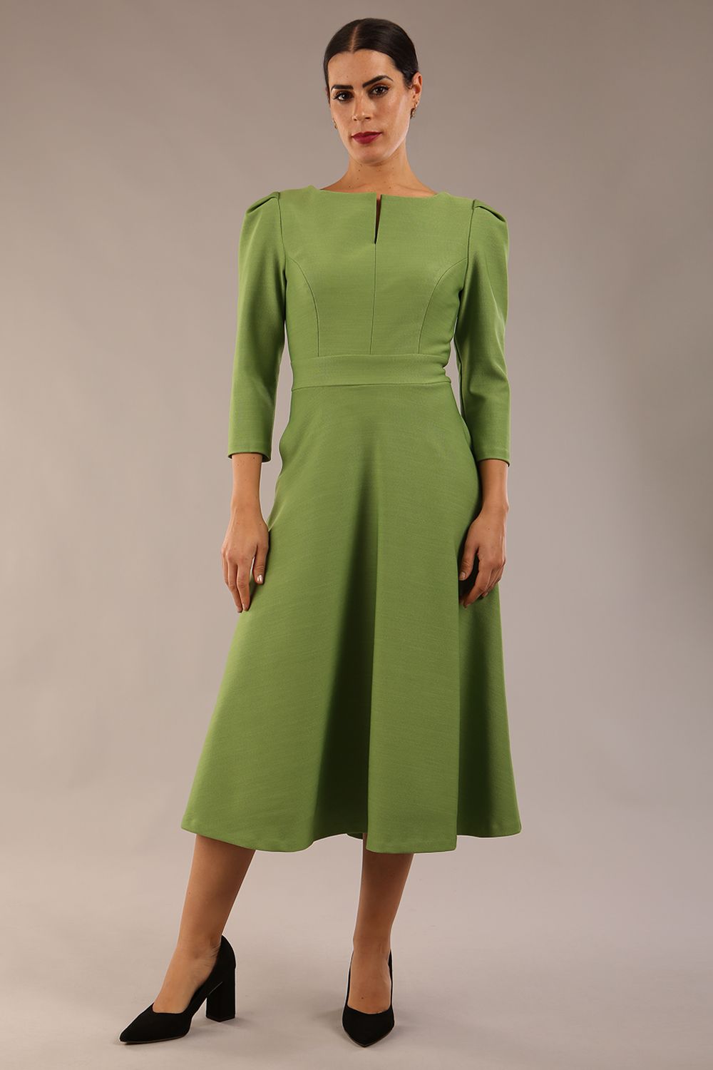 A model wearing a red, 3/4 sleeve A-line dress with pockets, featuring a boat neckline and vent at the centre back (Citrus Green)