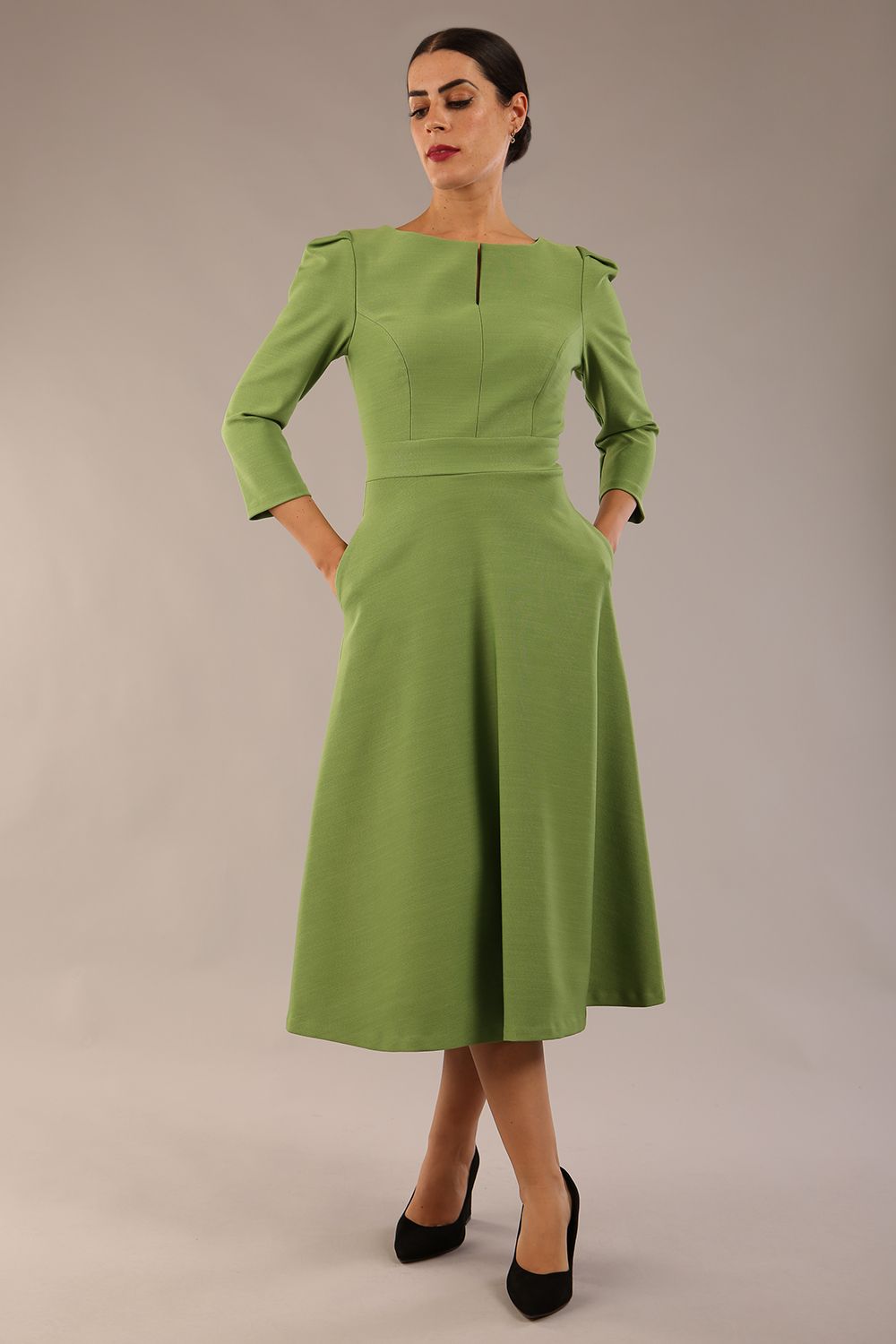 A model wearing a red, 3/4 sleeve A-line dress with pockets, featuring a boat neckline and vent at the centre back (Citrus Green)