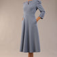 A model wearing a red, 3/4 sleeve A-line dress with pockets, featuring a boat neckline and vent at the centre back (Steel Blue)