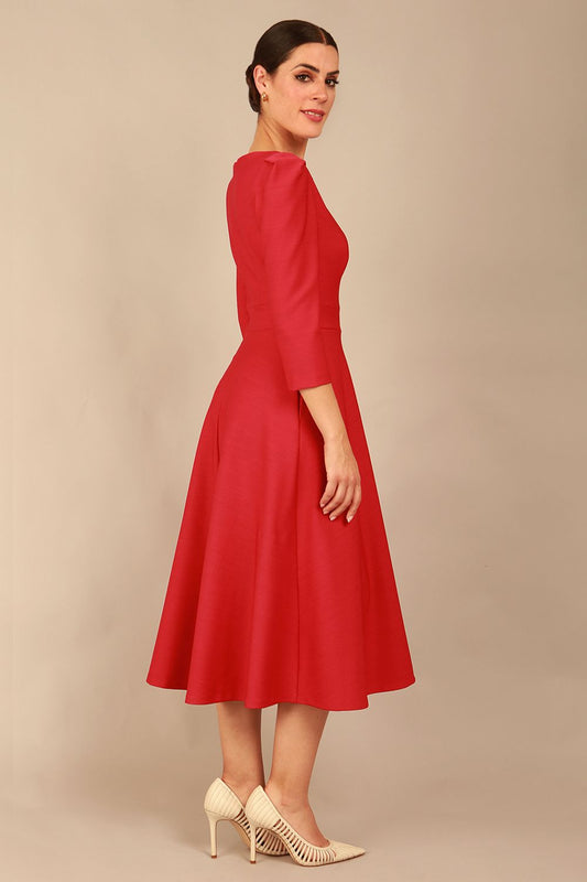 A model wearing a red, 3/4 sleeve A-line dress with pockets, featuring a boat neckline and vent at the centre back (Crimson Pink)
