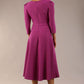 A model wearing a red, 3/4 sleeve A-line dress with pockets, featuring a boat neckline and vent at the centre back (Dawn Purple)