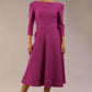 A model wearing a red, 3/4 sleeve A-line dress with pockets, featuring a boat neckline and vent at the centre back (Dawn Purple)