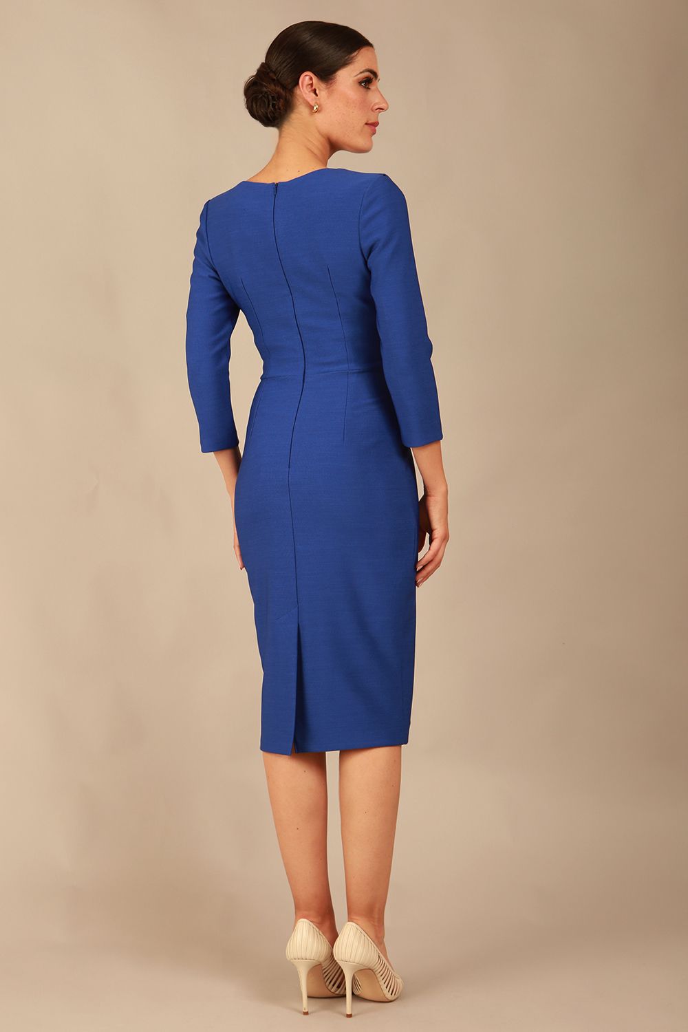 A woman modeling the diva catwalk  SEED Dolores cascade ruffle pencil dress in Monaco blue with a v-neckline and concealed zip at the back (Monaco Blue)