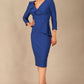 A woman modeling the diva catwalk  SEED Dolores cascade ruffle pencil dress in Monaco blue with a v-neckline and concealed zip at the back (Monaco Blue)
