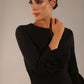 Model wearing the diva catwalk SEED Cicely rosette cuff pencil dress highlighting the asymmetric pleated waist and sculpted fit (Black)