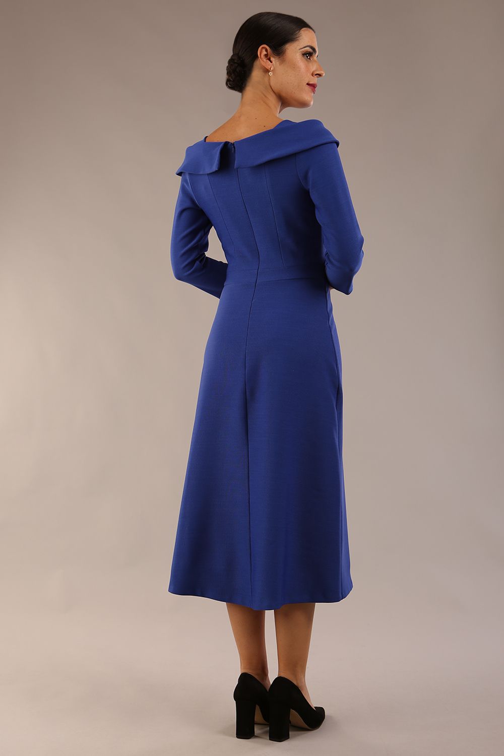 A model wearing a diva catwalk SEED Chrysanta sculptural collar dress 3/4 sleeve A-line dress with a round neckline and concealed zip at the back (Monaco Blue)