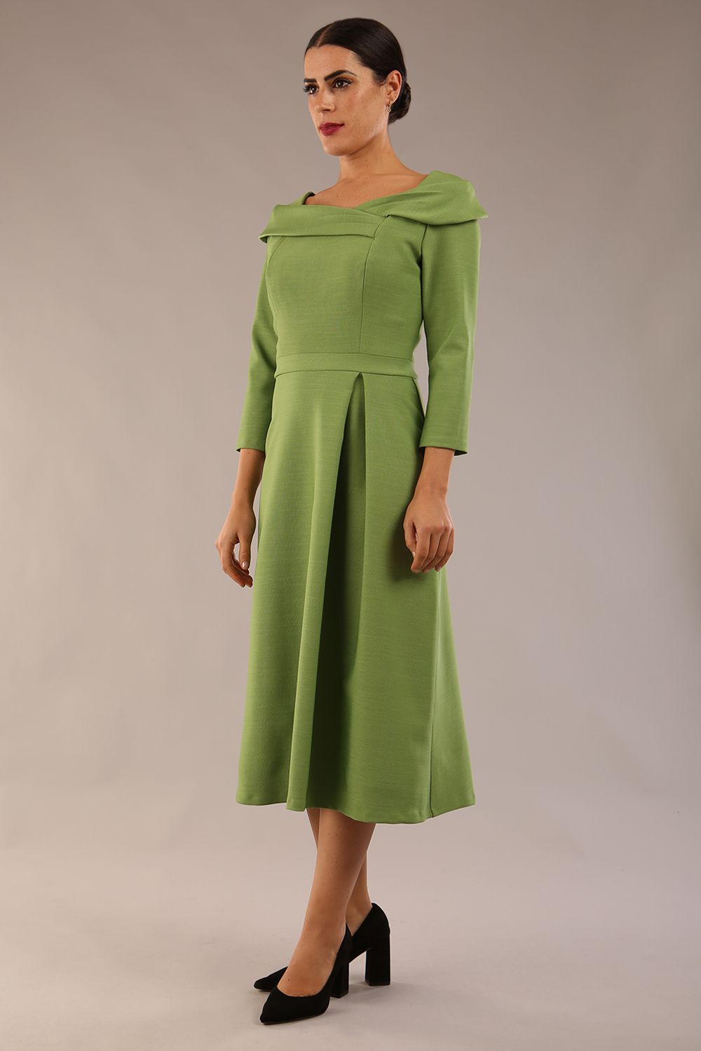 A model wearing a diva catwalk SEED Chrysanta sculptural collar dress 3/4 sleeve A-line dress with a round neckline and concealed zip at the back (Citrus Green)