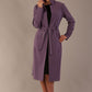 Model wearing the diva catwalk Paloma tie-waist midi coat in dusky lilac, with the belt cinched and collar up (Dusky Lilac)