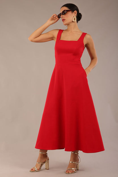 model wearing a diva catwalk Tamsin Square Neckline Swing Dress sleeveless style with a midaxi  length and side pockets in Scarlet Red colour