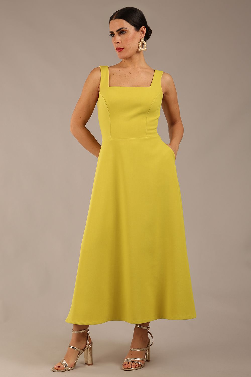 brunette model is wearing a diva catwalk Tamsin Square Neckline Swing Dress sleeveless style with a midaxi  length and side pockets in Citrus green colour front