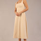 brunette model is wearing a diva catwalk Tamsin Square Neckline Swing Dress sleeveless style with a midaxi  length and side pockets in sandshell beige colour front