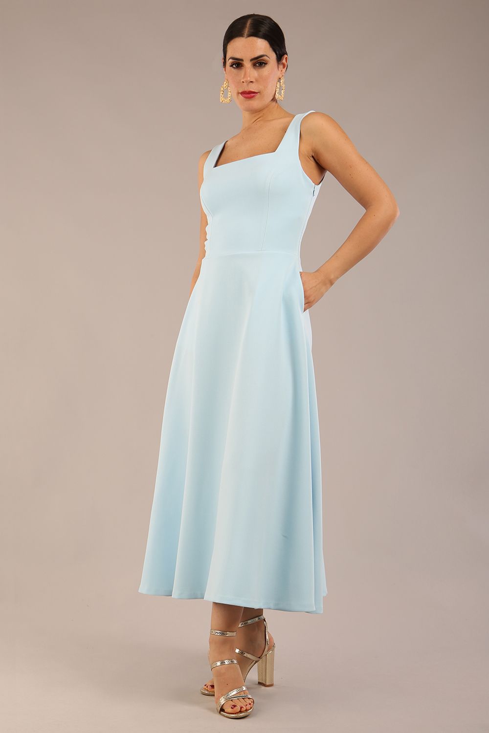 brunette model is wearing a diva catwalk Tamsin Square Neckline Swing Dress sleeveless style with a midaxi  length and side pockets in Sky blue colour front