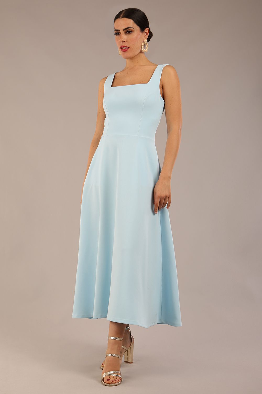 brunette model is wearing a diva catwalk Tamsin Square Neckline Swing Dress sleeveless style with a midaxi  length and side pockets in Sky blue colour front