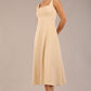 brunette model is wearing a diva catwalk Tamsin Square Neckline Swing Dress sleeveless style with a midaxi  length and side pockets in sandshell beige colour front