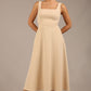 brunette model is wearing a diva catwalk Tamsin Square Neckline Swing Dress sleeveless style with a midaxi  length and side pockets in sandshell beige colour front