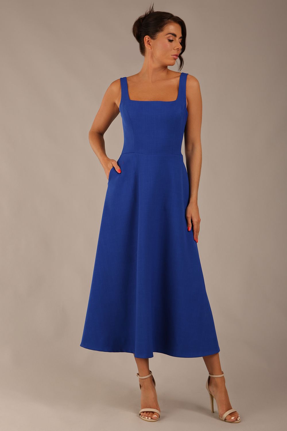 brunette model wearing a diva catwalk Tamsin Square Neckline Swing Dress sleeveless style with a midaxi  length and side pockets in cobalt blue colour front