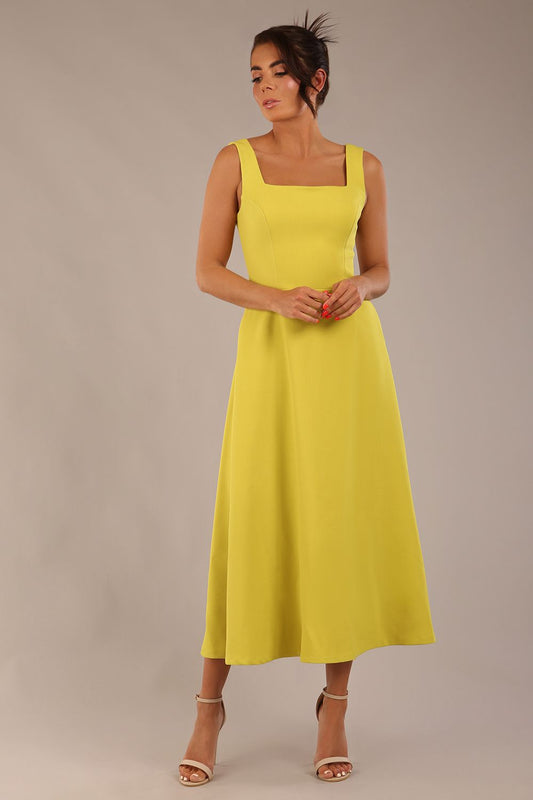 brunette model is wearing a diva catwalk Tamsin Square Neckline Swing Dress sleeveless style with a midaxi  length and side pockets in Citrus green colour front
