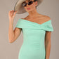 brunette model is wearing a diva catwalk Mariposa Longer Length Dress off the shoulder bardot neckline and midaxi length in mint green colour front image with hat and sunglasses