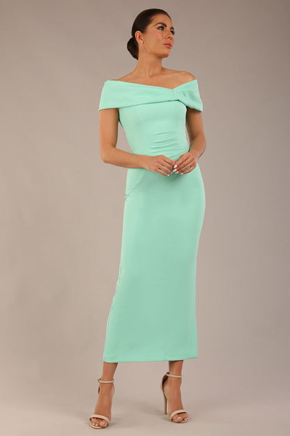 brunette model is wearing a diva catwalk Mariposa Longer Length Dress off the shoulder bardot neckline and midaxi length in mint green colour front image