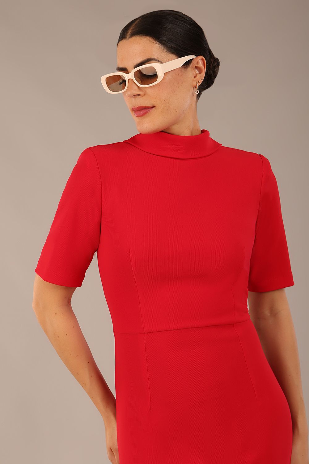 brunette model is wearing a diva catwalk Highmoor Short Sleeved Pencil Dress high neckline and shoulders pad in true red colour front image