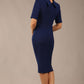 brunette model is wearing a diva catwalk Highmoor Short Sleeved Pencil Dress high neckline and shoulders pad in navy blue colour back image