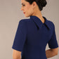 brunette model is wearing a diva catwalk Highmoor Short Sleeved Pencil Dress high neckline and shoulders pad in navy blue colour back image close up
