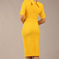 brunette model is wearing a diva catwalk Highmoor Short Sleeved Pencil Dress high neckline and shoulders pad in sunshine yellow colour back image