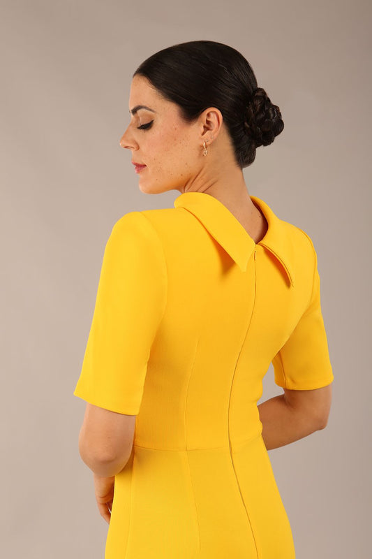 brunette model is wearing a diva catwalk Highmoor Short Sleeved Pencil Dress high neckline and shoulders pad in sunshine yellow colour back image close up