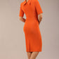 brunette model is wearing a diva catwalk Highmoor Short Sleeved Pencil Dress high neckline and shoulders pad in amber orange colour back image