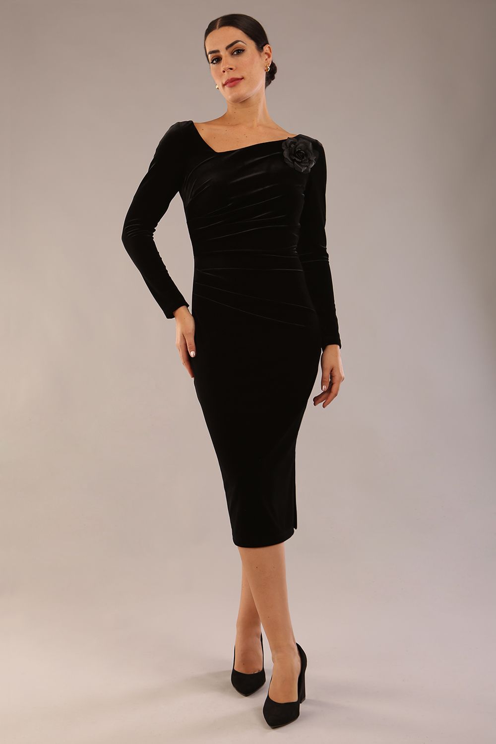 model is wearing a diva catwalk Renoir Long Sleeve Velvet Dress long sleeves midi length with side vent and asymmetric neckline and pleating details in black velvet